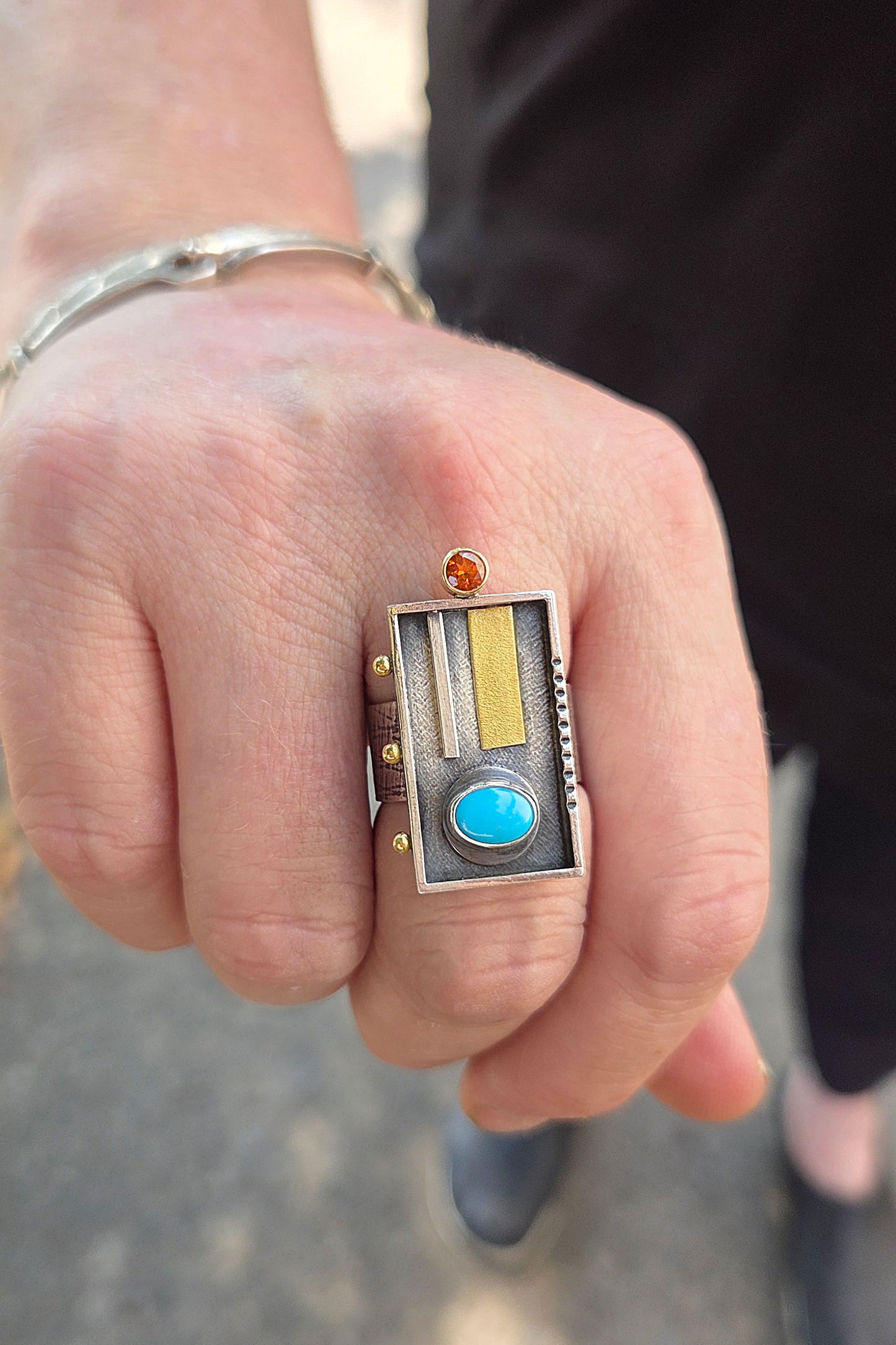 Close-up of a hand wearing a decorative ring with gemstones.
