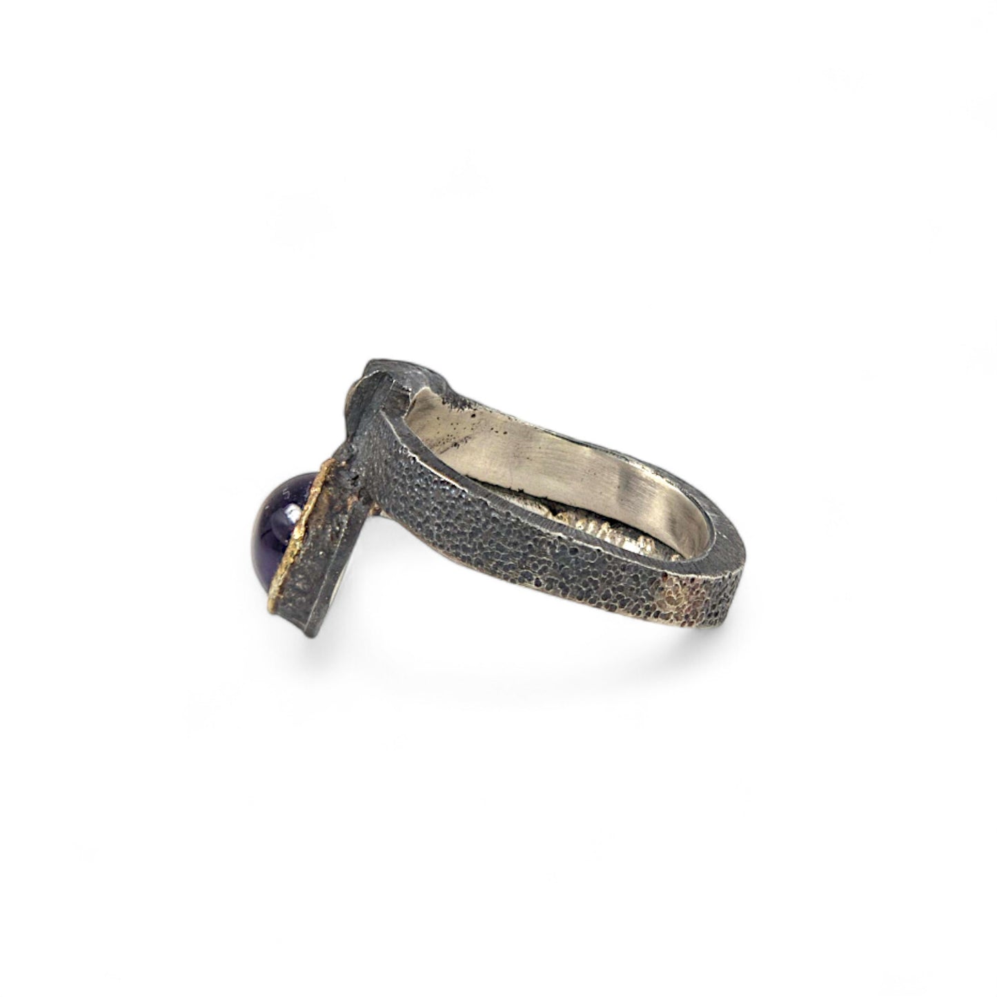 Silver ring with a textured band and purple gemstone on a white background