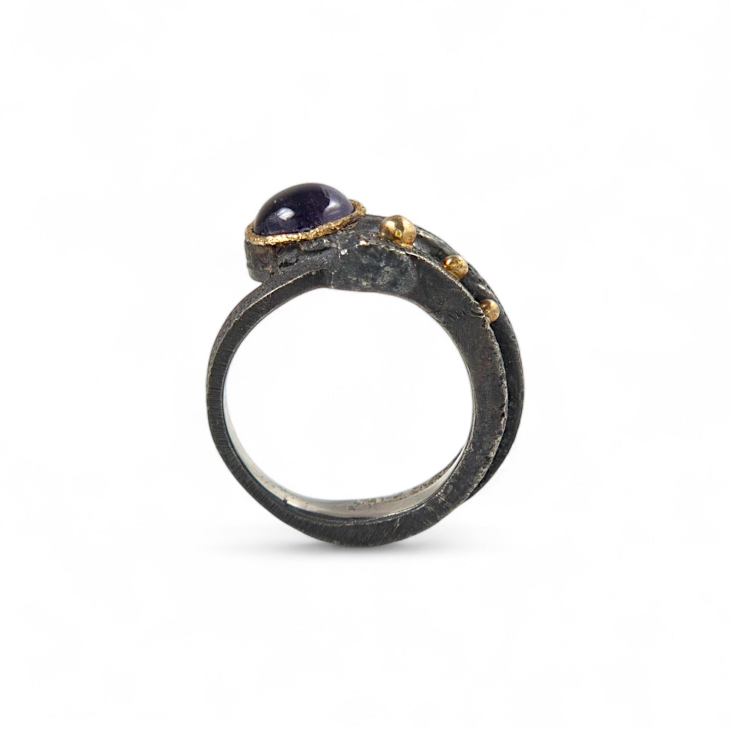 Ring with a purple gemstone and gold accents on a white background