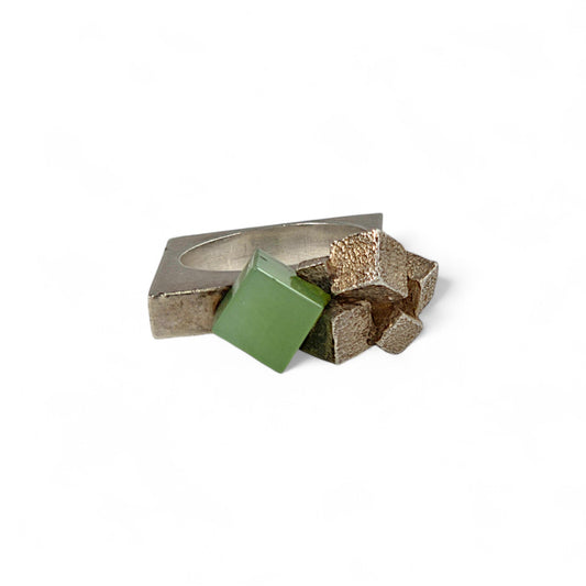 Silver ring with geometric design and green square on a white background