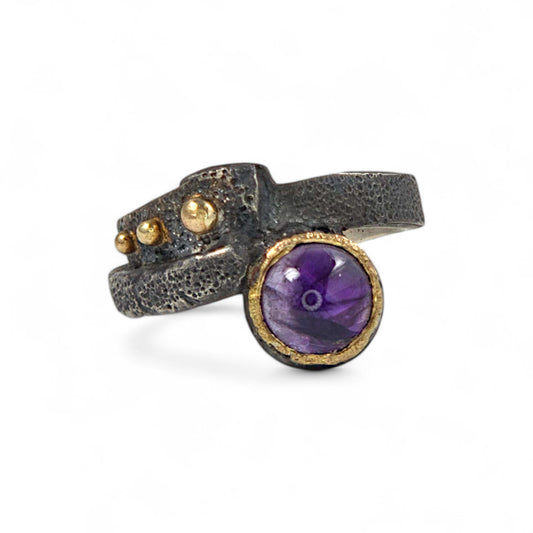 Unique ring featuring a purple gemstone on a white background