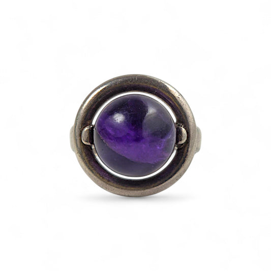 Ring with a purple gemstone and silver band on a white background